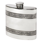 Silver hip flask with intricate designs on a white background