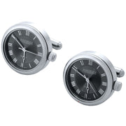 Pair of silver watch cufflinks with black faces and Roman numerals on a white background.
