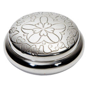Silver decorative object with intricate patterns on a white background