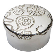 Silver round decorative box with intricate patterns on a white background
